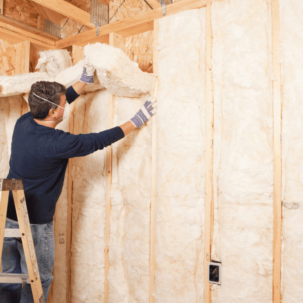 Fiberglass batts being installed in wall frame of New England home