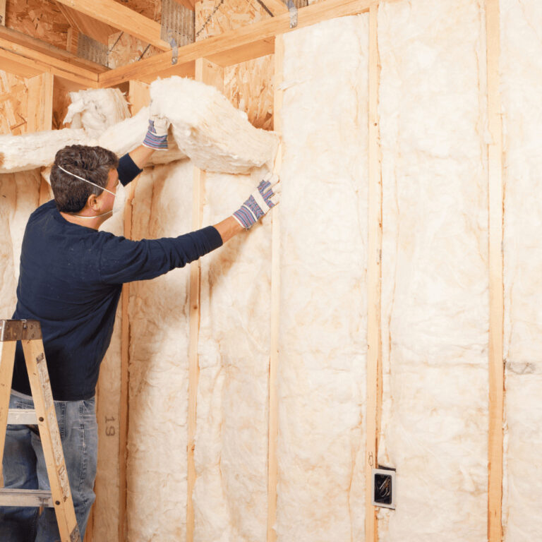 Fiberglass batts being installed in wall frame of New England home